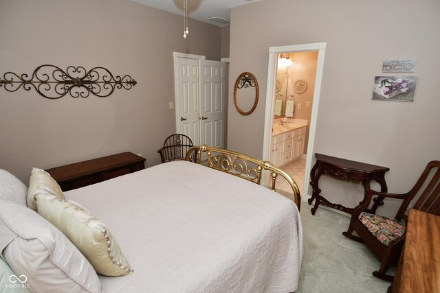 bedroom with ensuite bath and light carpet