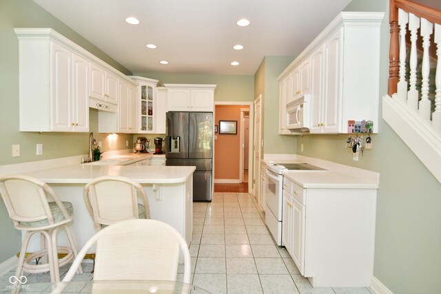 kitchen featuring a sink, white appliances, a breakfast bar area, a peninsula, and recessed lighting