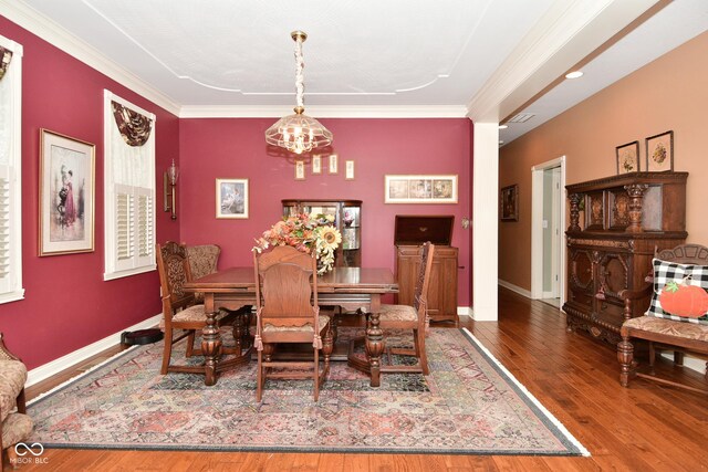 dining space featuring baseboards, an inviting chandelier, ornamental molding, and wood-type flooring