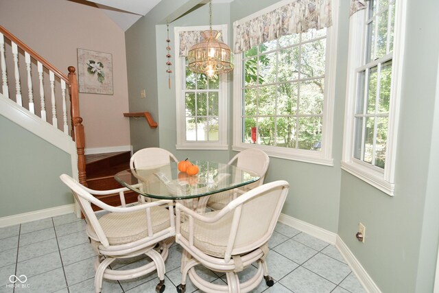dining room featuring lofted ceiling, light tile patterned floors, baseboards, a chandelier, and stairs