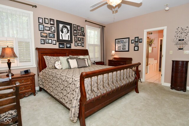 bedroom featuring a ceiling fan, ensuite bathroom, baseboards, carpet flooring, and visible vents