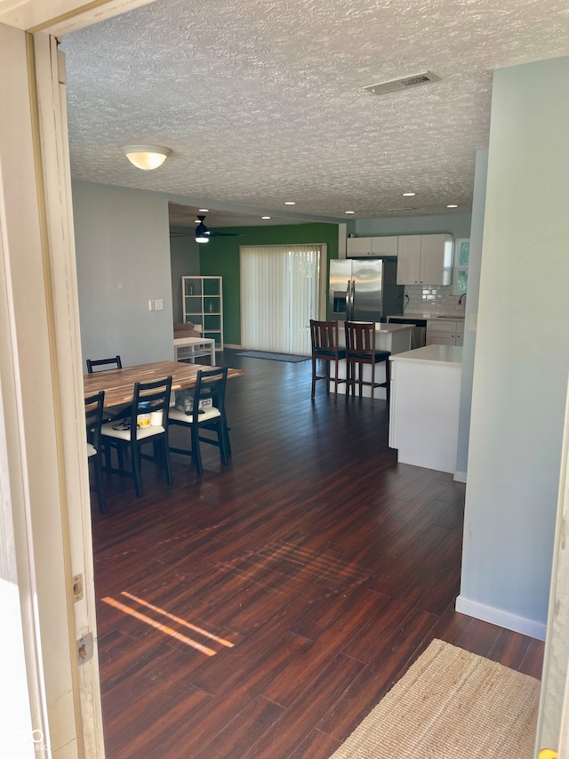 dining space with a textured ceiling and dark wood-type flooring