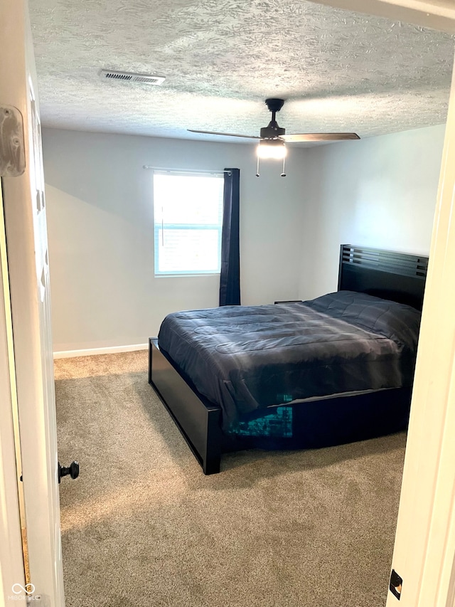 carpeted bedroom featuring ceiling fan and a textured ceiling