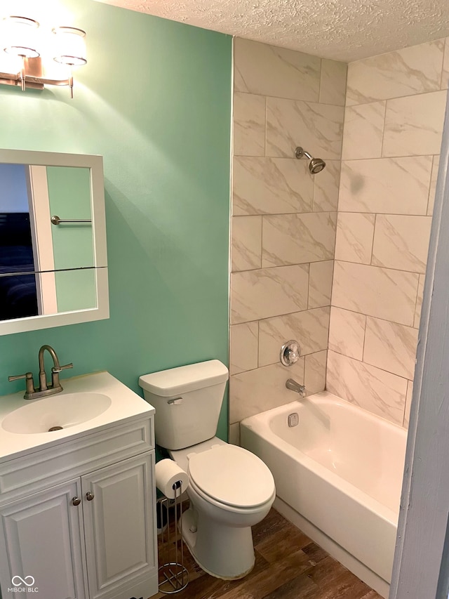 full bathroom with vanity, toilet, tiled shower / bath combo, a textured ceiling, and hardwood / wood-style floors