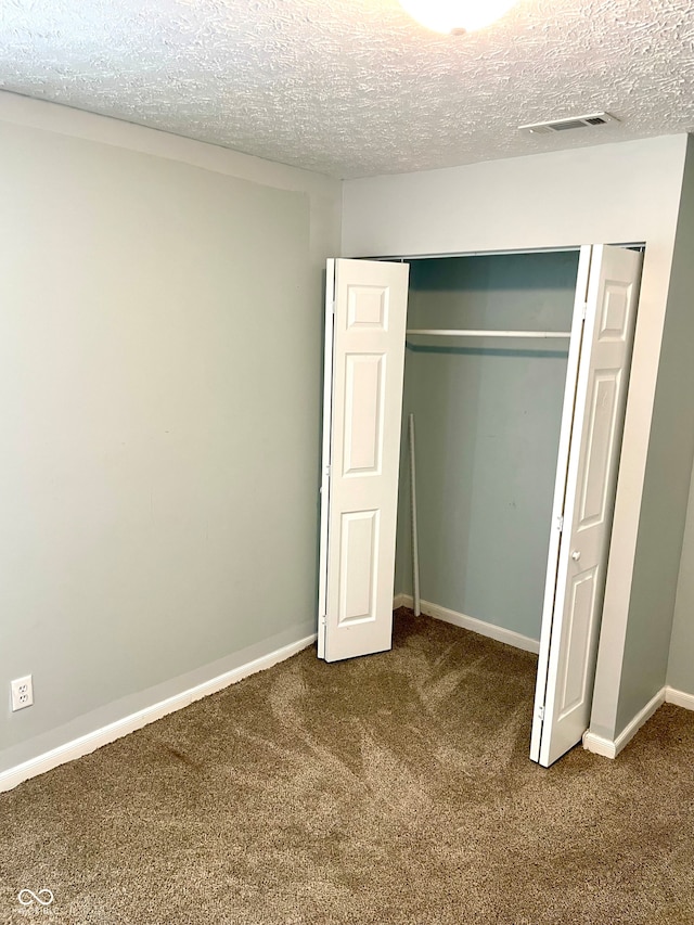 unfurnished bedroom featuring a closet, a textured ceiling, and carpet floors