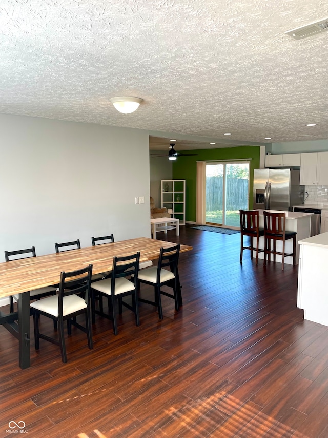 dining space featuring a textured ceiling and dark wood-type flooring