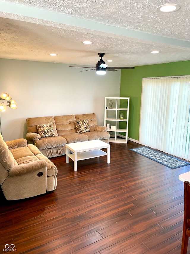 living room with a textured ceiling, ceiling fan, and dark hardwood / wood-style flooring