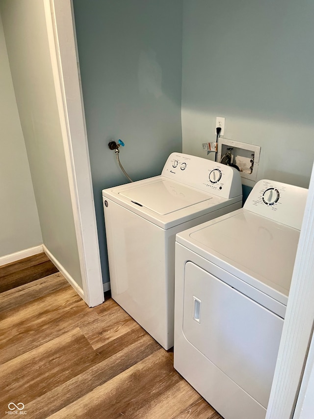 clothes washing area with hardwood / wood-style flooring and washer and dryer