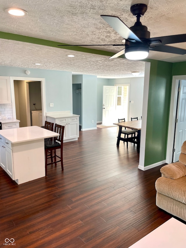 living room featuring a textured ceiling, ceiling fan, and dark hardwood / wood-style flooring