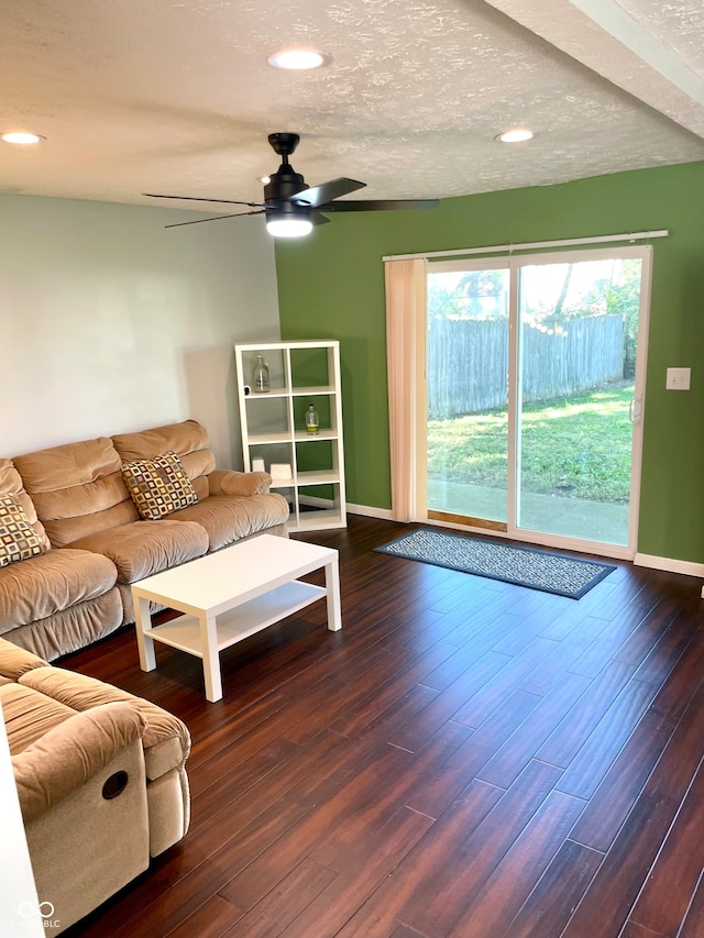 living room with a textured ceiling, ceiling fan, and dark hardwood / wood-style flooring