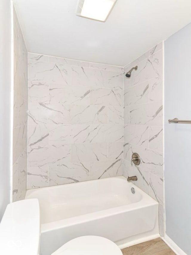 bathroom featuring tiled shower / bath combo and toilet