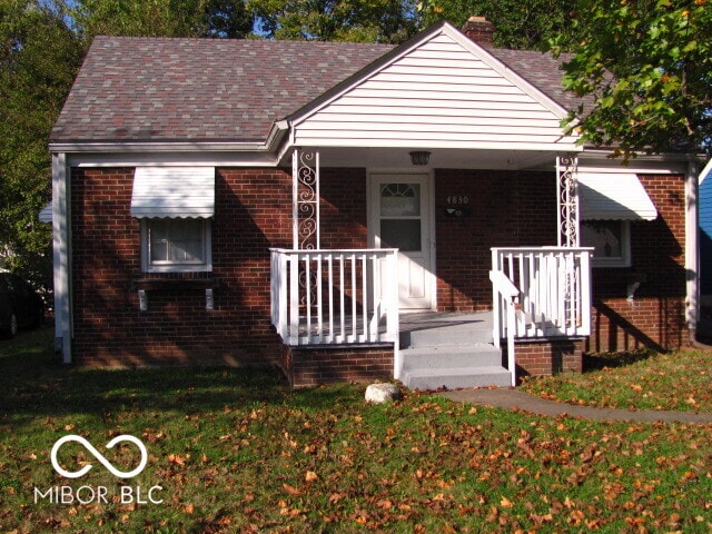 bungalow-style home featuring covered porch and a front yard