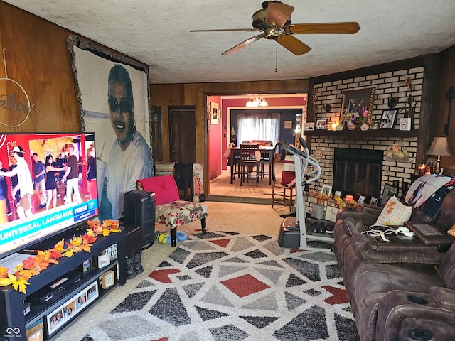 carpeted living room featuring a brick fireplace, wood walls, ceiling fan, and a textured ceiling