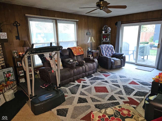 carpeted living room featuring wooden walls and ceiling fan