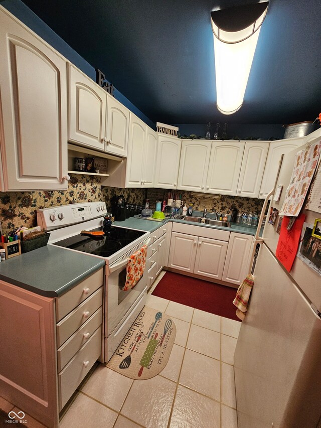 kitchen with white cabinetry, electric stove, light tile patterned floors, and sink