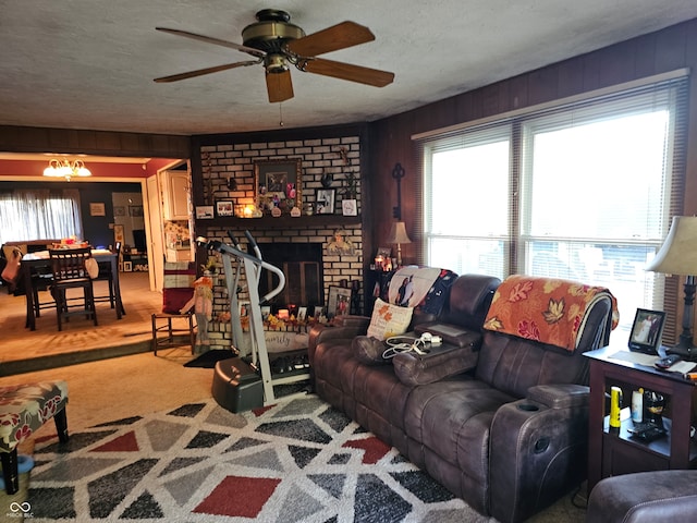 living room with a brick fireplace, a textured ceiling, a healthy amount of sunlight, and ceiling fan