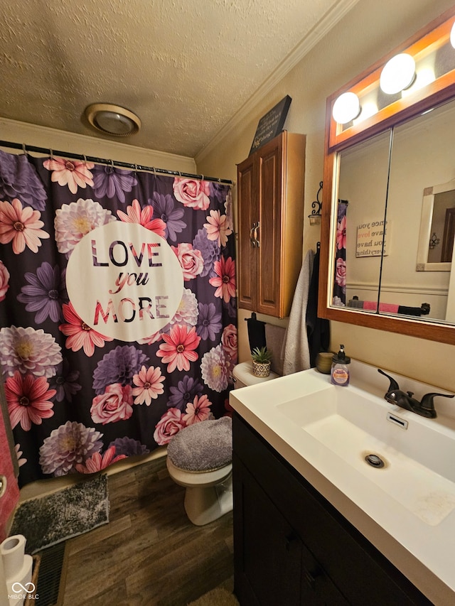 bathroom featuring a textured ceiling, hardwood / wood-style flooring, ornamental molding, vanity, and toilet