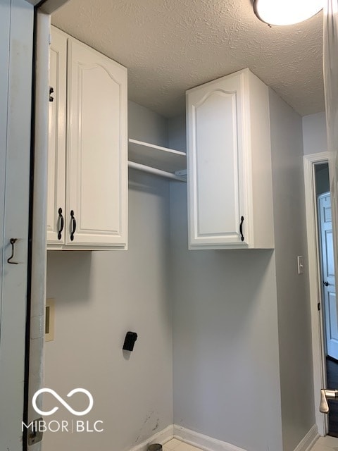 laundry area with a textured ceiling, washer hookup, and cabinets