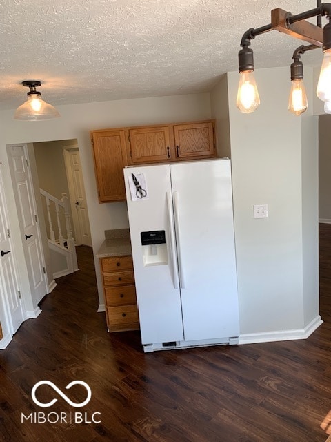 kitchen featuring white refrigerator with ice dispenser, a textured ceiling, dark hardwood / wood-style floors, and pendant lighting