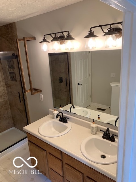 bathroom with vanity, a shower with shower door, and a textured ceiling