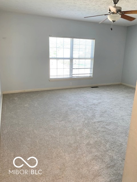 carpeted spare room with ceiling fan and a textured ceiling