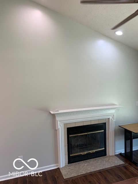 interior details featuring a tiled fireplace, wood-type flooring, and a textured ceiling