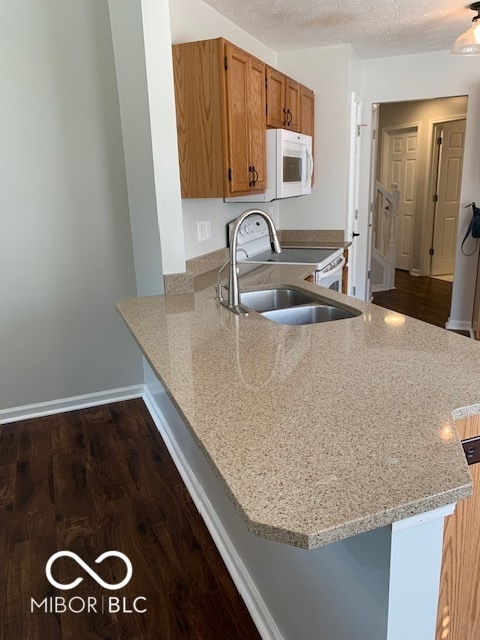 kitchen with sink, kitchen peninsula, a textured ceiling, range, and dark hardwood / wood-style floors