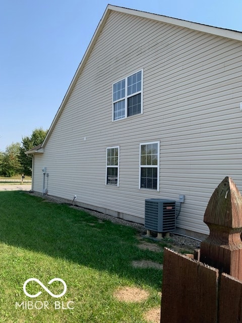 view of property exterior featuring central AC unit and a lawn