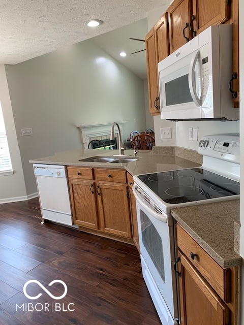 kitchen featuring white appliances, dark hardwood / wood-style floors, sink, and a textured ceiling