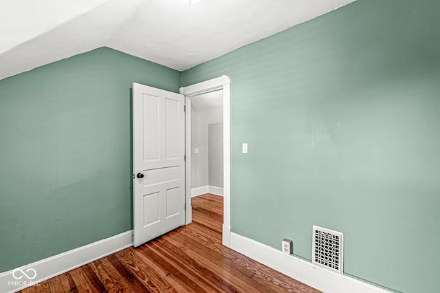 unfurnished bedroom featuring wood-type flooring and vaulted ceiling