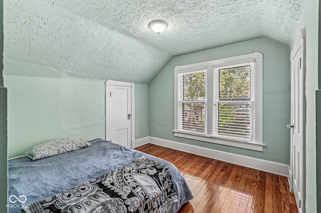 bedroom featuring a textured ceiling, vaulted ceiling, and dark wood-type flooring