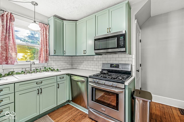 kitchen featuring light hardwood / wood-style flooring, green cabinets, appliances with stainless steel finishes, and backsplash