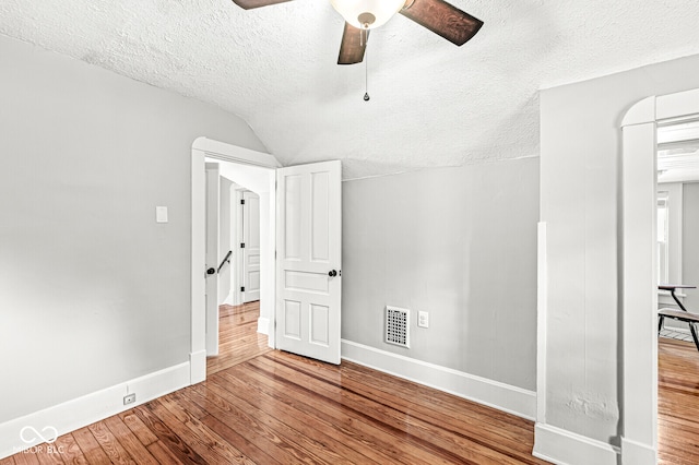 spare room featuring lofted ceiling, a textured ceiling, hardwood / wood-style flooring, and ceiling fan