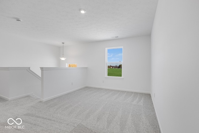 unfurnished room with light colored carpet and a textured ceiling