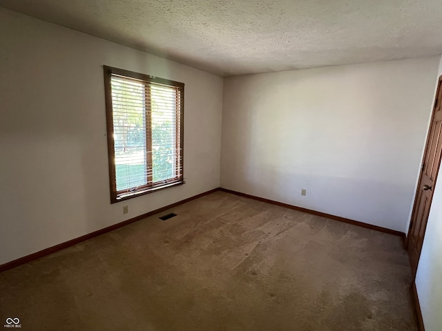 carpeted empty room with a textured ceiling