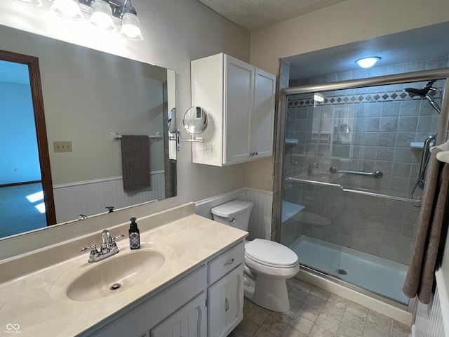 bathroom featuring walk in shower, a textured ceiling, vanity, and toilet