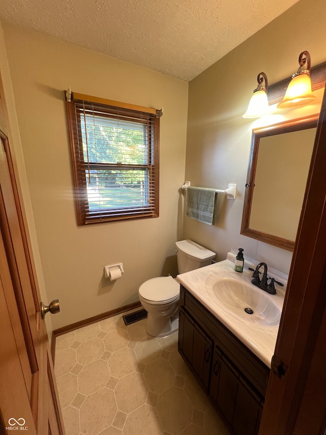 bathroom featuring vanity, toilet, and a textured ceiling