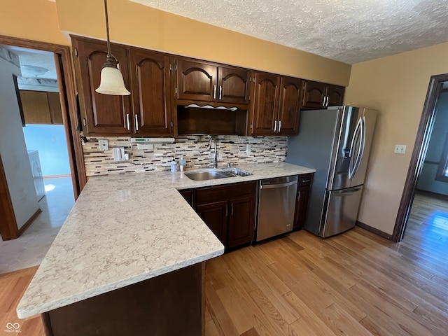 kitchen featuring light hardwood / wood-style flooring, stainless steel appliances, and hanging light fixtures