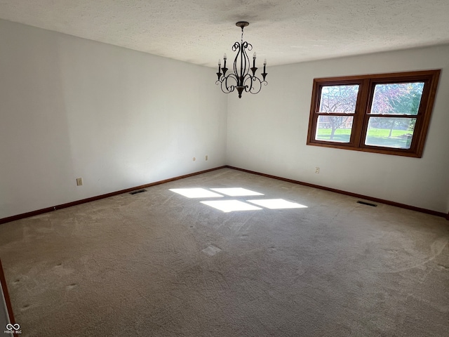 unfurnished room with a textured ceiling, a chandelier, and carpet