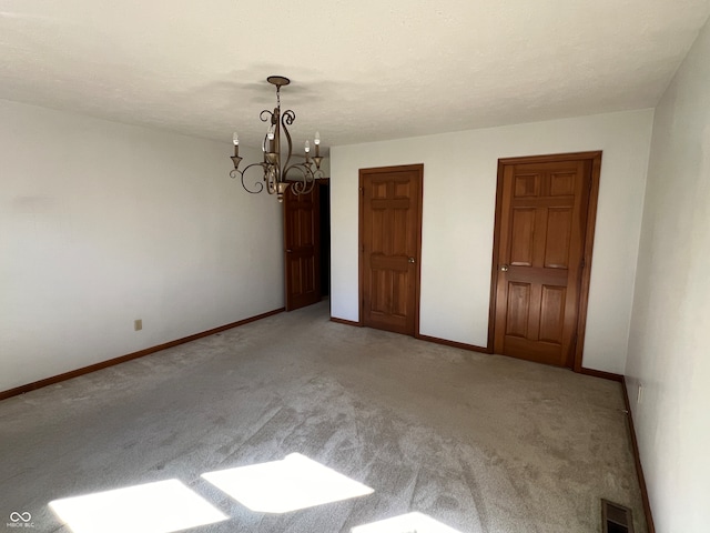 carpeted empty room with a chandelier