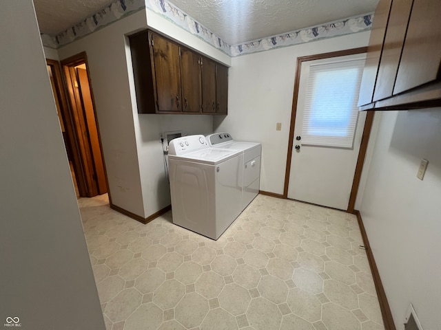 laundry area featuring cabinets, washing machine and clothes dryer, and a textured ceiling