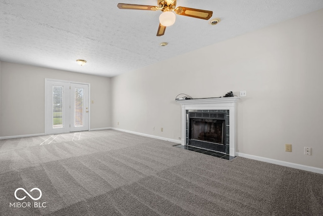 unfurnished living room featuring ceiling fan, a textured ceiling, a fireplace, and dark colored carpet