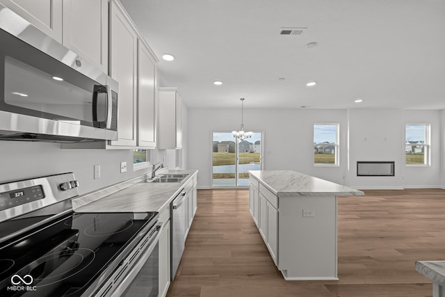 kitchen with a center island, white cabinets, stainless steel appliances, and a notable chandelier