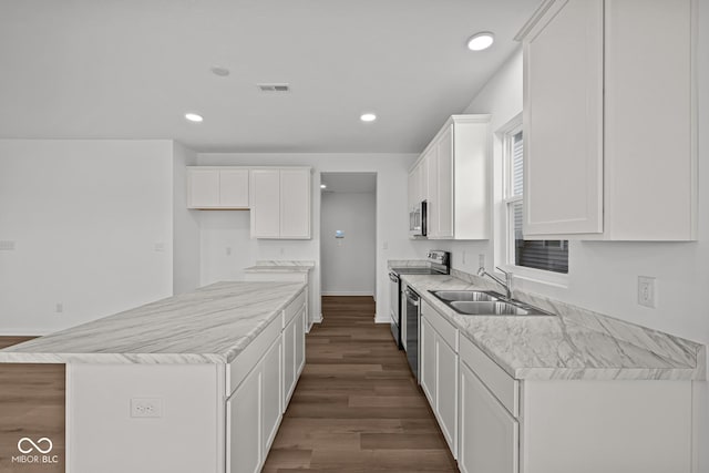 kitchen with sink, dark wood-type flooring, stainless steel appliances, a kitchen island, and white cabinets