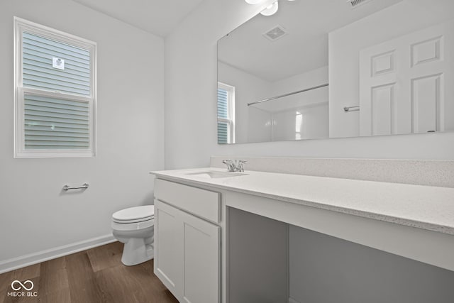 bathroom featuring walk in shower, vanity, wood-type flooring, and toilet