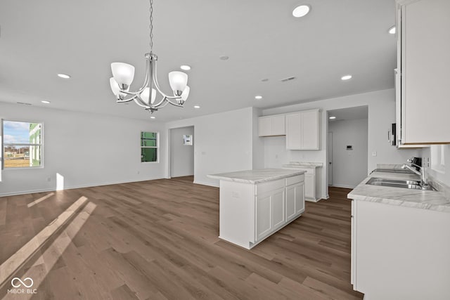 kitchen featuring an inviting chandelier, a kitchen island, hardwood / wood-style floors, pendant lighting, and white cabinets