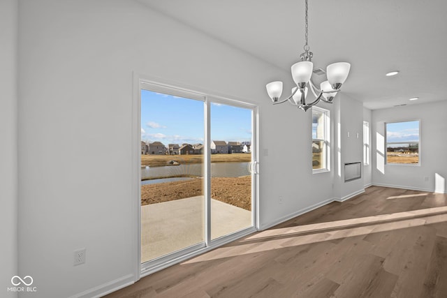 interior space with a chandelier, hardwood / wood-style floors, and a water view