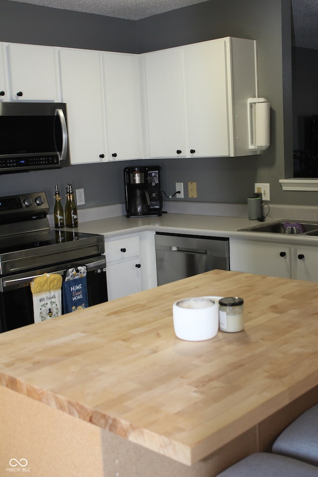 kitchen with sink, a textured ceiling, white cabinets, and stainless steel appliances