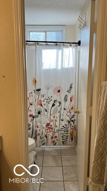 bathroom with a textured ceiling, toilet, tile patterned flooring, and a shower with shower curtain