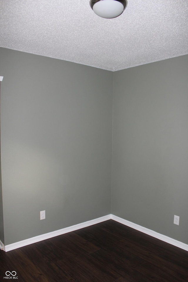 empty room featuring a textured ceiling and dark wood-type flooring